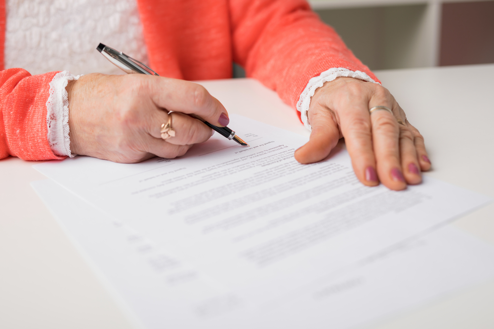 femme âgée signant un contrat d'assurance vie