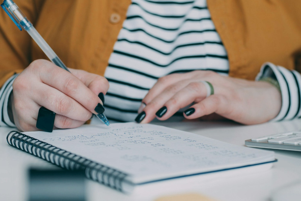 femme calculant sur papier les mensualités de ses crédits en cours